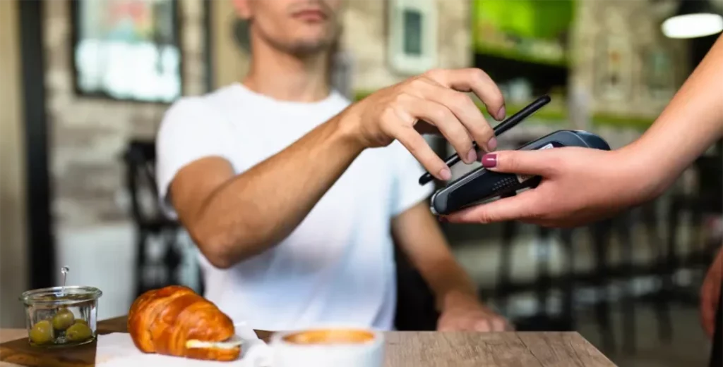 A cafe customer pays with their smartphone on a mobile payment device without square error codes.